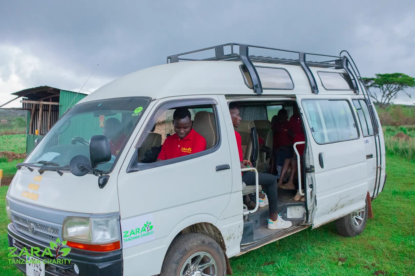 The charity minibus parked at the school, children in red polo shirts sitting in the open doorway.