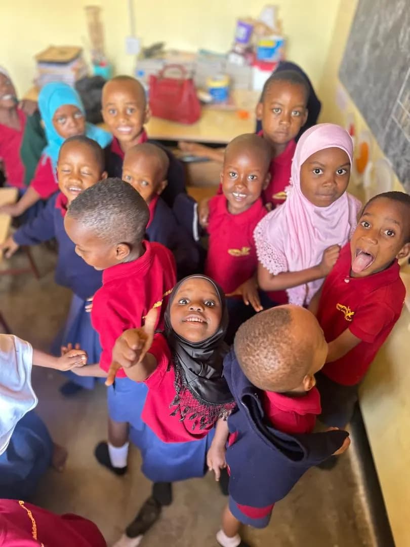 Primary school children crowding up to the camera in their red and navy uniforms, laughing.